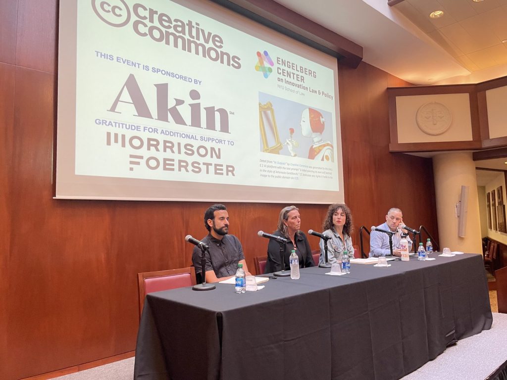 A panel of four people seated at a table on stage below a slide with an image of a robot painting at an empty easel, saying: Creative Commons, Engleberg Center on Innovation Law & Policy, this event sponsored by Akin, gratitude for additional support to Morrison Foerster.