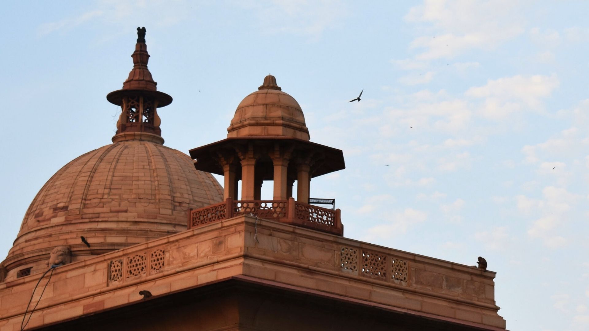 A photo of the top of a red brick building in Delhi with a clear blue sky behind.